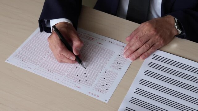 マークシート方式の解答用紙にペンで回答を記入する手元