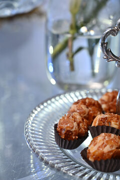 gourmet caramelized nut truffles on crystal tray close up, elegant party desserts with crisp caramel topping on glass plate, brazilian party candy stock photography with copy space