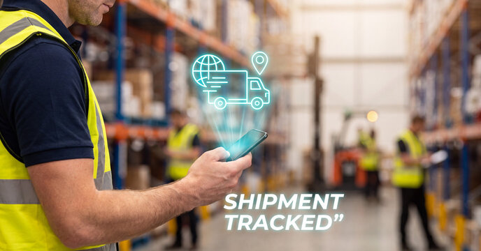 Warehouse worker using mobile phone with digital delivery tracking hologram in a large distribution center for global logistics management