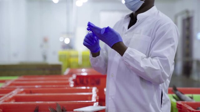 Factory worker getting dressed in protective gear in food plant
