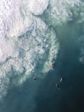 Aerial view of people swimming in the turquoise waters of Mullaloo Beach with white sea foam swirling in the ocean at Perth, Western Australia, Australia.