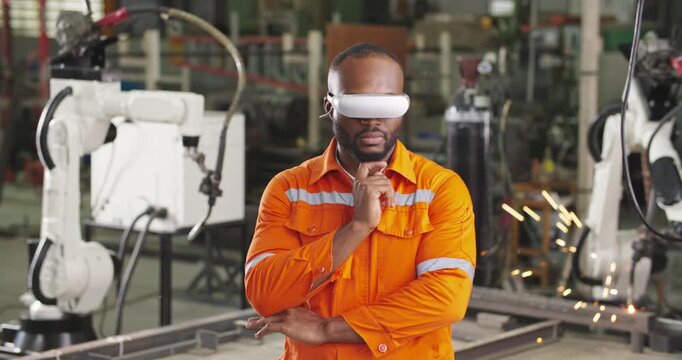 Professional industrial engineer using a virtual reality headset control and operate an experimental automation robotic arm machine. High Tech Industry 4.0 Factory. Innovation and futuristic concept.
