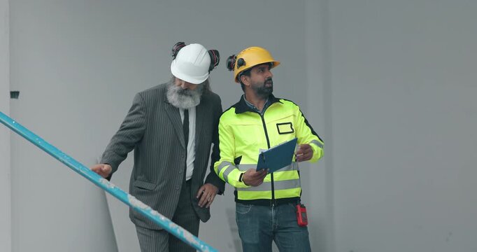 Engineer and businessman inspecting house construction site while discussing building project