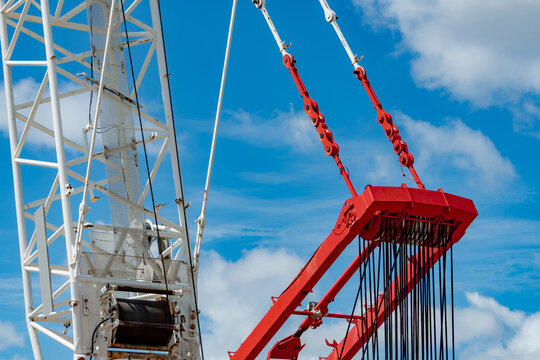 Closeup construction crane boom with lifting cables and pulley system against blue sky, heavy industrial equipment supporting infrastructure development, engineering projects and modern construction.
