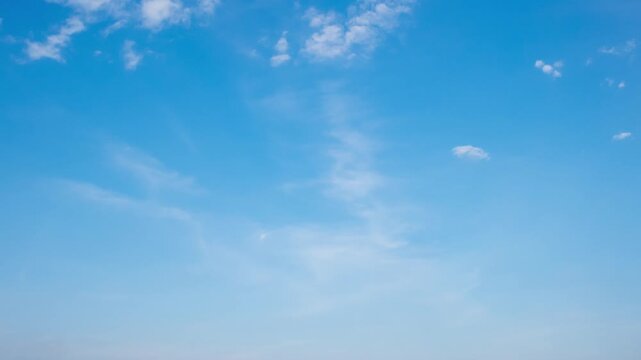 Peaceful daytime sky time-lapse with soft white clouds flowing in a deep blue atmosphere.