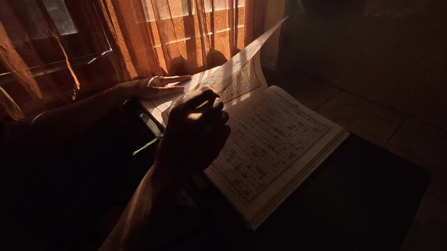 Gresik Indonesia - August 5, 2026: Landscape Side Angle Slow Motion Shot of Turning Pages of Large Book on Table During Morning Sunshine