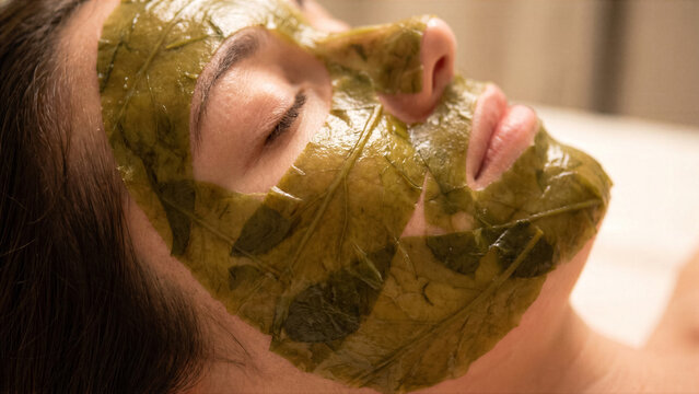 High end spa photo of person face covered in face mask sheet made of real green seaweed