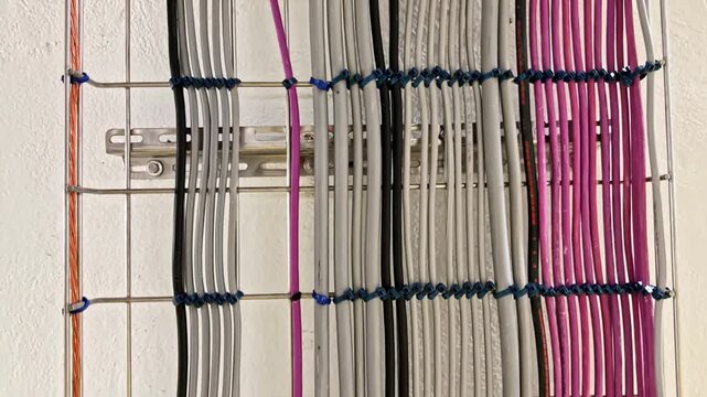 View of organized electrical cables on a wire rack with grey, black, and purple wires secured by cable ties in an industrial installation in France.