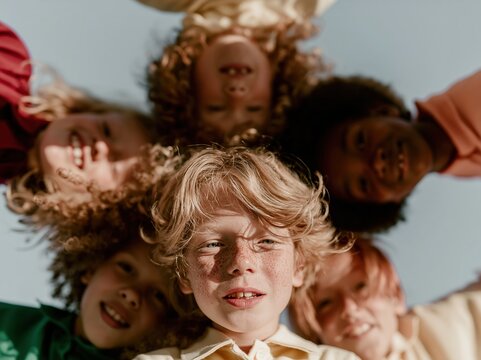 Diverse group of joyful children peering down into a circle, showing natural skin textures and freckles in a soft pastoral setting for friendship and community layouts