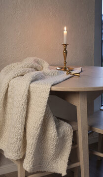 Cozy Knit Blanket on Wooden Table with Lit Candle