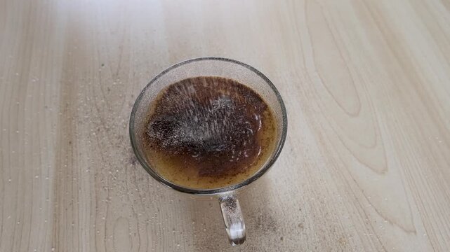 Instant Coffee Powder Falling into Glass Cup of Hot Water