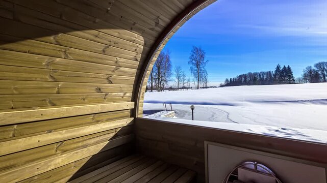 View of a wooden sauna interior looking out through a large window at a frozen lake and snow-covered fields in Riga, Latvia.