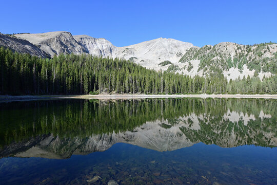 Mount Sopris reflected in calm water of second Thomas Lake In Maroon Bells-Snowmass Wilderness on clear sunny summer morning.