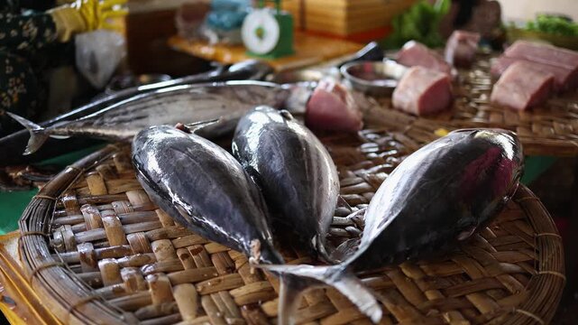 Fresh whole tuna fish displayed on woven bamboo tray at Vinh Hai market in Nha Trang, Vietnam. Close up view of raw skipjack or bonito tuna at traditional Asian seafood wet market stall, food concept.