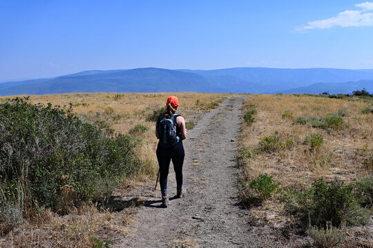 Woman hikes along exposed section of Thomas Lakes Trail in White River National Forest near Carbondale, Colorado on sunny summer morning.
