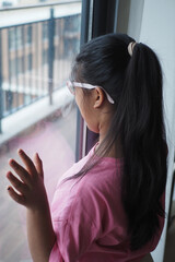 Obraz premium Child looks out the window while standing in a room