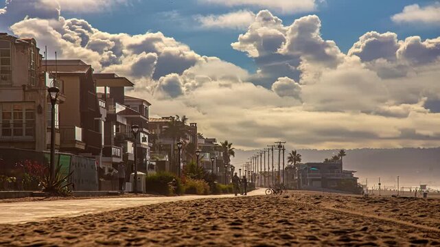 View of people cycling on a beach path with buildings and a cloudy sky in San Francisco, California, United States.