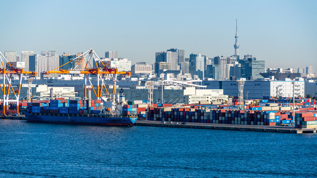Tokyo port scenic view with container ship and containers on dock with cranes and skyline with Skytree in background in Tokyo Japan