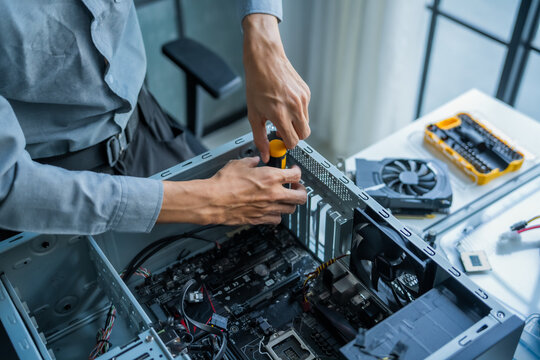 Asian IT engineer man fixing mainboard in pc case on working table