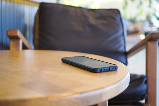 Black smartphone on wooden table in cafe setting. lost smart phone concept 