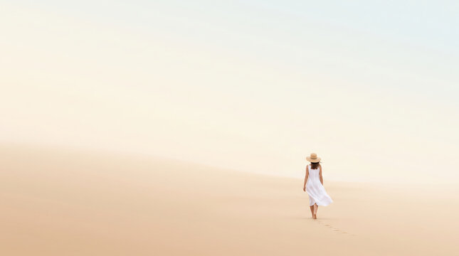 Woman walking alone on desert sand dune.