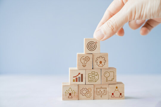 Hands holding wooden blocks with business icons, business strategy management, set goal and target, collaboration business concept