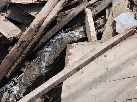 Clear water flowing through concrete debris and wooden planks at a ruined site