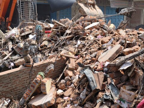 Excavator clearing building rubble at a construction demolition site