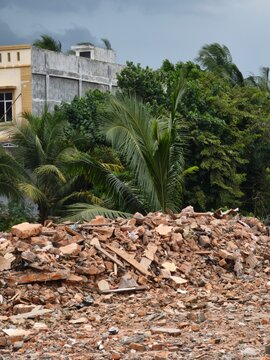 Pile of rubble from a demolished brick building with tropical palm trees in daylight