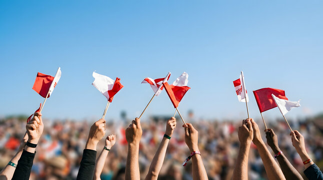 Crowd waving red and white flags at outdoor event