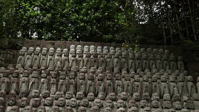 Ancient stone statues at a Buddhist temple in Japan, arranged closely together as a sacred religious display. Travel, culture, meditation and heritage concept.