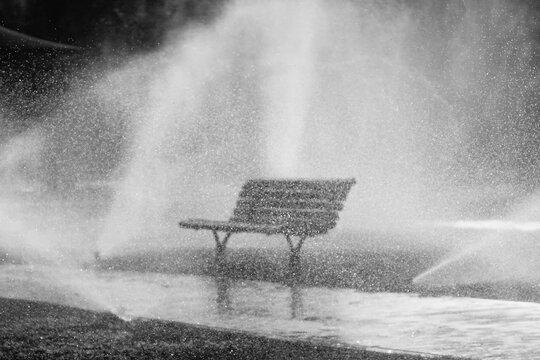 Banc public dans un parc pendant irrigation, monochrome, horizontal 