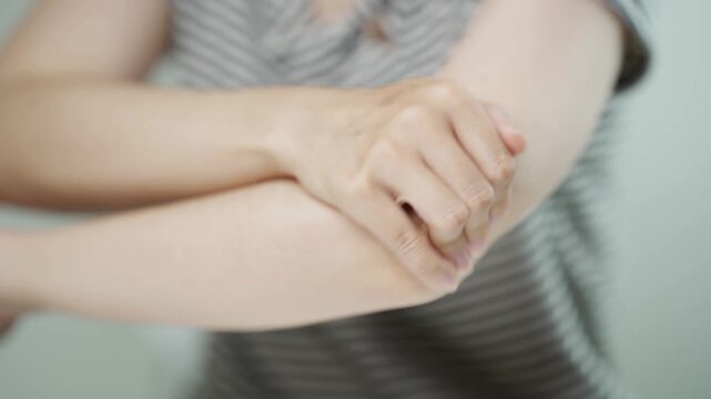 Close up of a woman holding her painful elbow, representing elbow pain, tendonitis, muscle strain, joint inflammation, repetitive strain injury, rehabilitation, healthcare, recovery, and wellness.