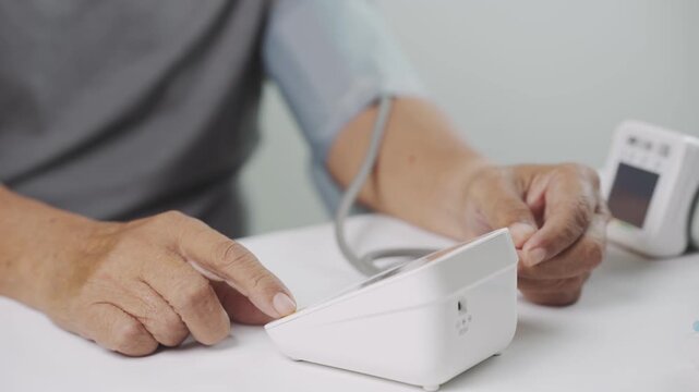 Close-up of a senior adult using a digital blood pressure monitor at home to check blood pressure and cardiovascular health. Healthcare monitoring, hypertension prevention, self care and healthy aging