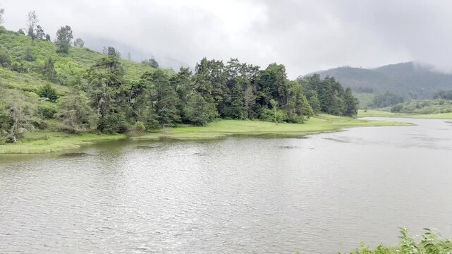 4K footage of scenic lake and green forest hills at Bandipur Tiger Reserve Karnataka, with calm water, misty mountains and lush wildlife habitat, showcasing safari tourism and nature conservation.