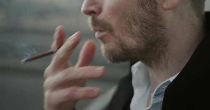 Close-up of a man lighting a cigarette and exhaling a cloud of smoke after taking a drag