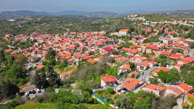 Aerial view of Omodos village in Cyprus. Dense red rooftops, stone houses and surrounding green hills create a scenic Troodos mountain village panorama.