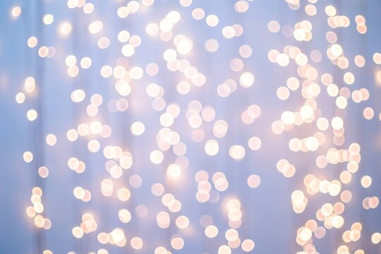 Soft light blue bokeh background with glowing blurred fairy lights creating a magical festive abstract texture for winter holiday design