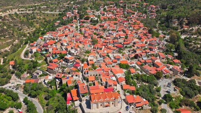 Wide aerial view of Omodos in Cyprus. The compact village, terracotta rooftops and surrounding vineyards create a scenic countryside panorama.