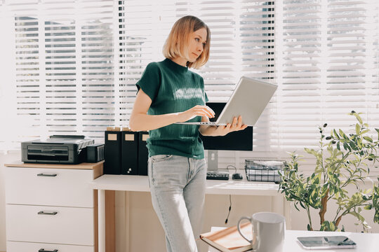 Concept of business working, Businesswoman sitting while writing and checking business analytic document  report  and holding tablet with computer pc, smartphone on desk in her workstation.