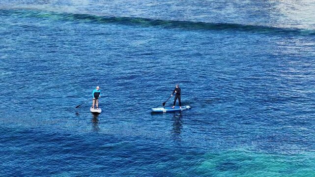 Two Men Stand Up Paddleboarding on Blue Ocean Water