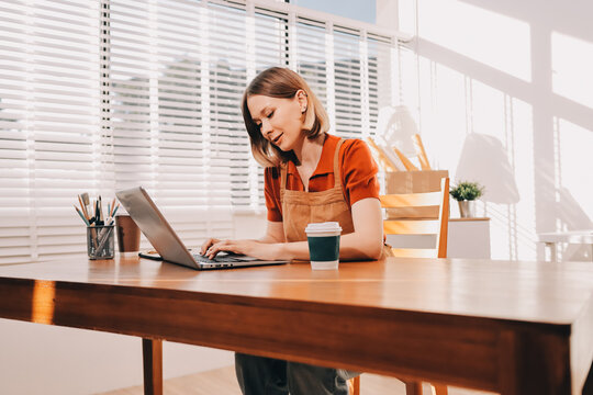 Young woman works on a touchpad, feeling comfortable at cozy home office with a green plant on the background
