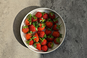 Fresh ripe strawberries on the plate, close up view. background. red. green leaves, leaf. health. sunlight, sunshine. black, dark, shadows. side. front. copy space, empty, free, negative, text,  © Muhammad