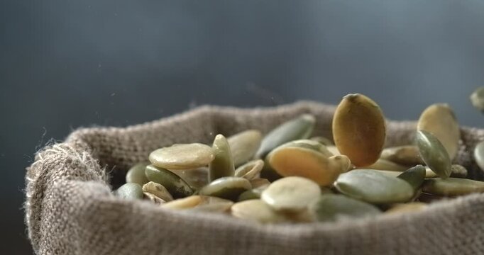 Pumpkin seeds falling into burlap sack in super slow motion