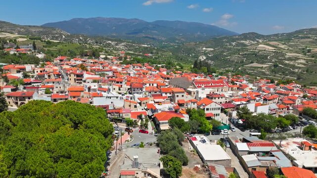 Aerial view of Omodos in Cyprus. The red-roofed village spreads across the hillside with vineyards and countryside in the background.