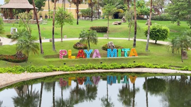Wide establishing of Playa Mita tourist sign reflected in pond at Punta de Mita, backdrop with nobody