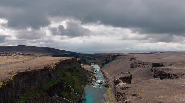 Aerial symmetrical ascend along Sigoldugljufur canyon with waterfalls in Iceland, drone backdrop with stormy sky