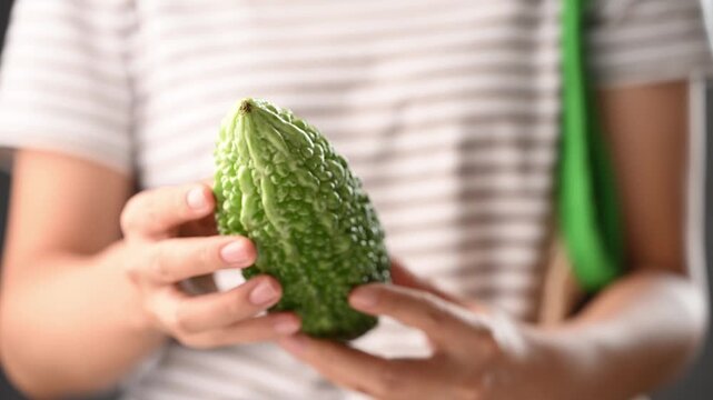Woman hands holding and selecting a fresh bitter gourd for cooking