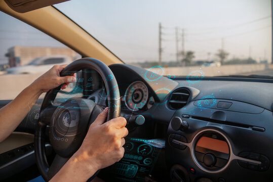 Driver inside a car with holographic digital interface showing vehicle data and EV tech, photo manipulation, not AI.