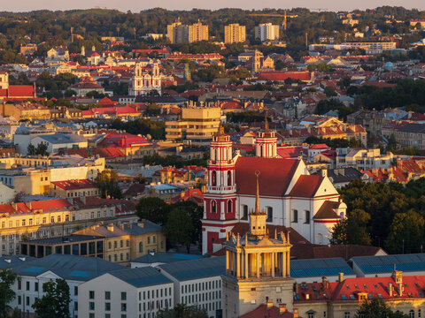 Aerial view of the historic Old Town of Vilnius featuring the Church of St. Philip and St. James, red-tiled rooftops, and golden hour light in Vilnius, Vilnius County, Lithuania.